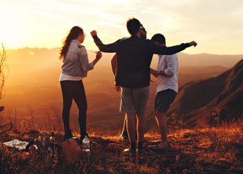 four-person-standing-at-top-of-grassy-mountain-697244