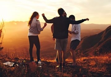 four-person-standing-at-top-of-grassy-mountain-697244