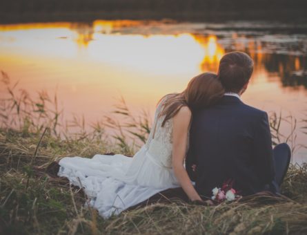 wedding-couple-sitting-on-green-grass-in-front-of-body-of-70737